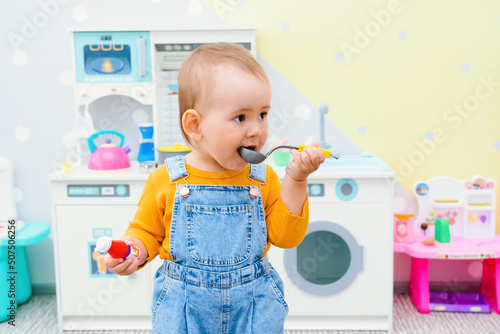 A small child holds a ladle in his hands in the children's play kitchen