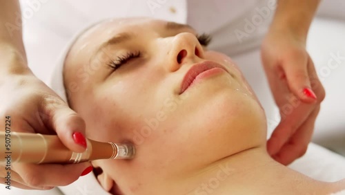 Beautician cosmetologist doing procedure fractional microneedle mesotherapy with Dermapen. Hardware cosmetology in clinic salon for client.	 photo