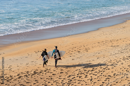 Couple on the beach with surfboards in the afternoon photo