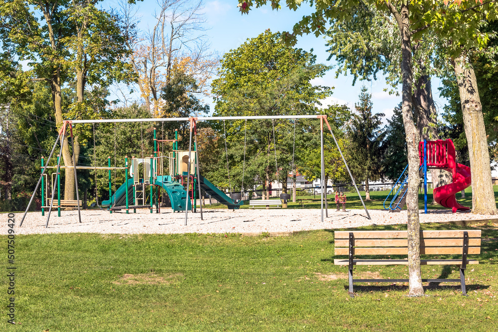Fototapeta premium Deserted playgrond for children with slides and swings in a public park on a sunny autumn day
