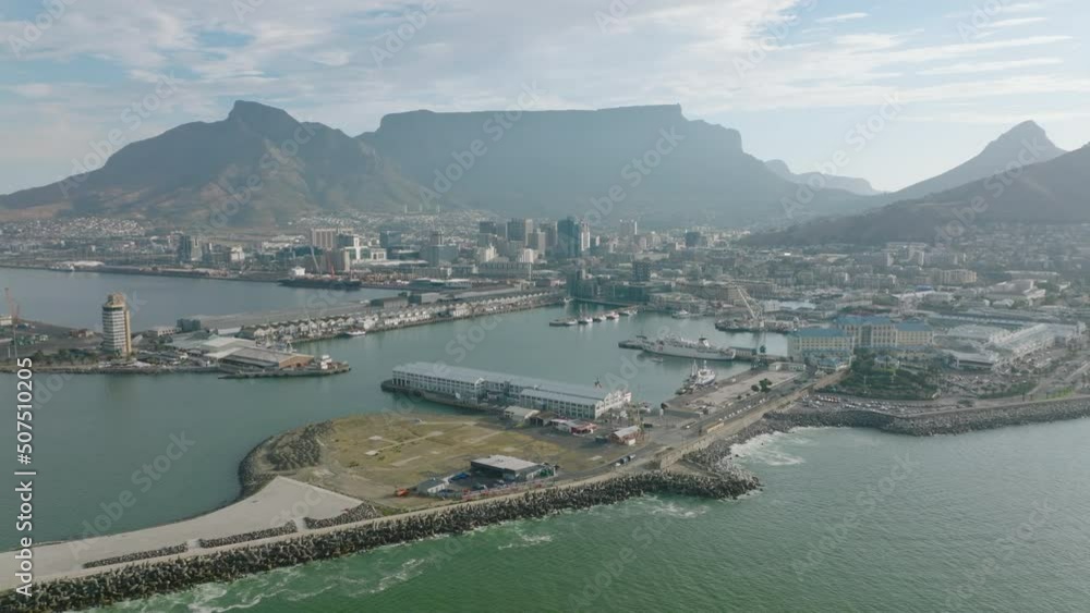 Fly around sea coast. Complex of building in Victoria and Alfred Waterfront. Flat topped mountain ridge above city in background. Cape Town, South Africa Fly around sea coast. Complex of building in Victoria and Alfred Waterfront. Flat topped mountain ridge above city in background. Cape Town, South Africa