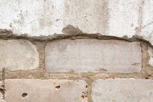 The texture (background) of the destroyed cement old wall (plaster, concrete) from under which the brickwork is visible.