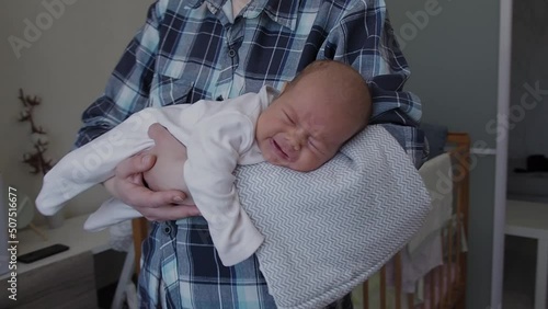 woman rocking crying and screaming baby girl on arms at daytime. One month new born child tired and hungry  photo