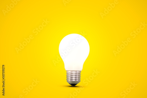 Glowing light bulb isolated on a bright yellow background. photo