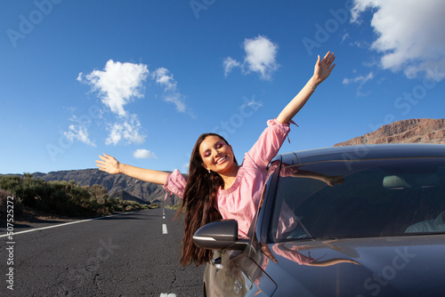 Young happy beautiful woman goes to summer travel trip in car.