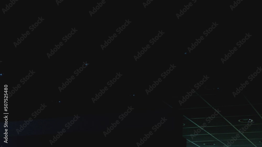 Many Circle Led lamps built into the ceiling glowing in the dark . To include and switch off . White rounded lights turns on alternately on ceiling of dark, industrial room. Lighting equipment concept