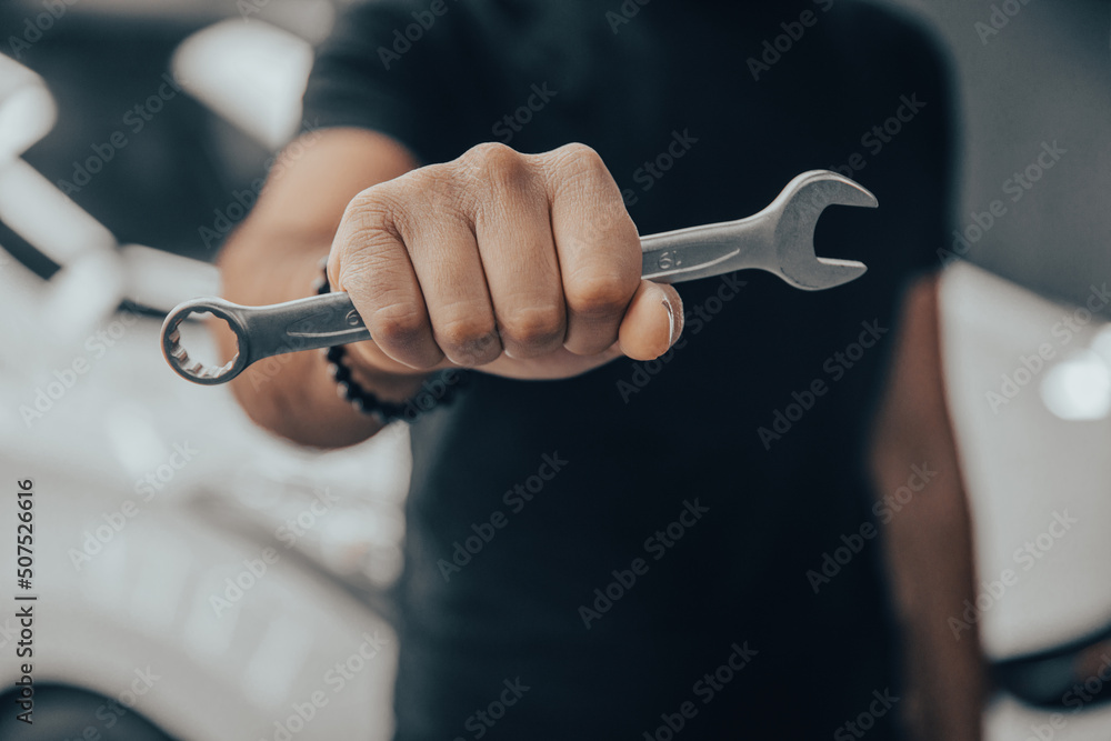 Hand holding a wrench with a car repairs