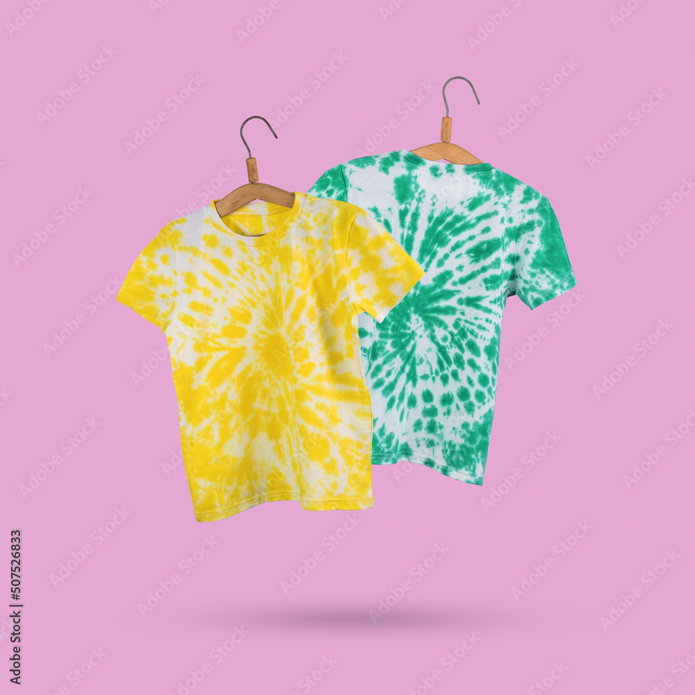 Blue and green tie dye T-shirts on a pink background. Stock Photo