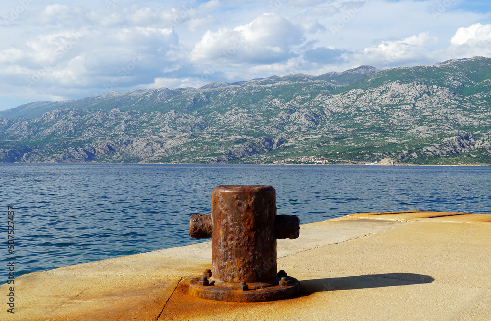 Rusty mooring on the sea dock in front of a high mountain Rusty mooring on the sea dock in front of a high mountain