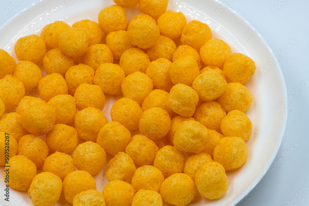 Selective focused cheese puff balls. Pile of cheese balls isolated on white background. Plate full of cheese puff balls isolated Selective focused cheese puff balls. Pile of cheese balls isolated on white background. Plate full of cheese puff balls isolated