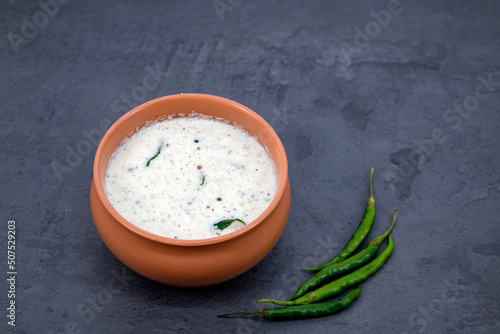 Fresh made Indian food, chutney, Coconut chutney in a bowl with raw coconut. Served with dosa, idli, vadai, Pongal. Selective focused home made coconut chutney in isolated white background. photo