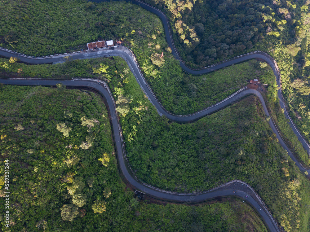 Overhead Drone photo of the road on the slopes of a mountain and surrounded by dense forest. It located in Mount Telomoyo in clear weather Overhead Drone photo of the road on the slopes of a mountain and surrounded by dense forest. It located in Mount Telomoyo in clear weather