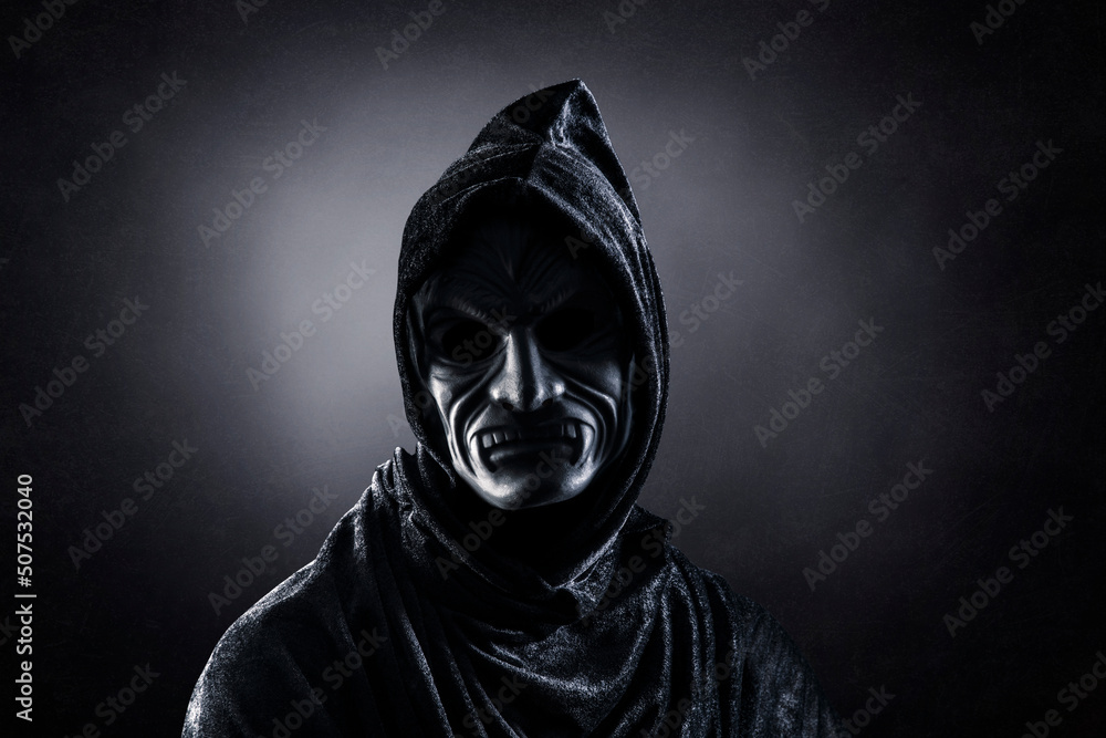 Vampire with cape showing his scary teeth over dark misty background Vampire with cape showing his scary teeth over dark misty background