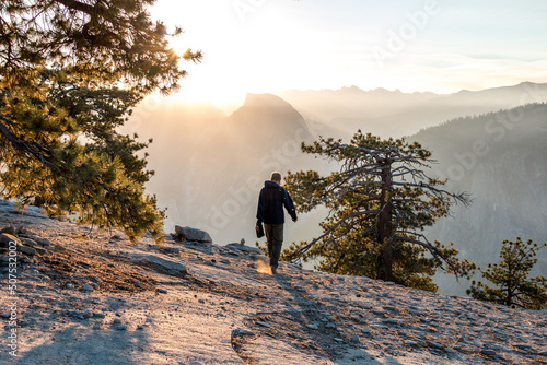 Hiker at sunrise with half dome in distance