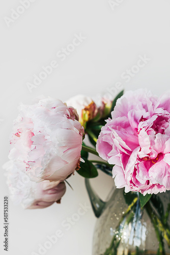 Blooming fluffy white pink peony flower bouquet on elegant minimal pastel beige background. Creative floral composition. Stunning botany wallpaper or vivid greeting card.