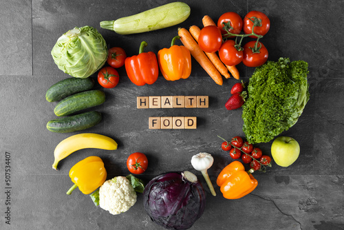 Organic vegetables and fruits on dark. Text Healthy food on wooden cubes
