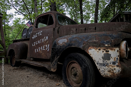 Old rusty broken down truck with oak barrels casks in back hauling moonshine an illicit alcohol liquor made illegally by people in the southern United States. photo