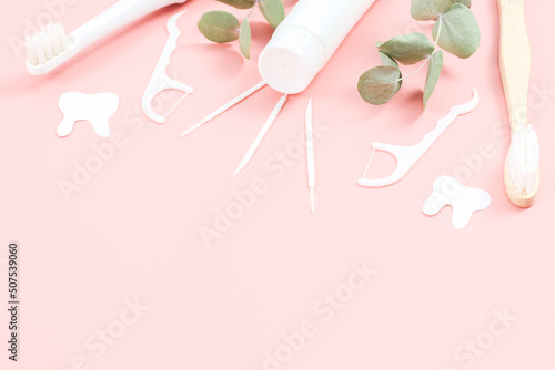 Bamboo toothbrushes, electric, tube of toothpaste, dental floss, toothpicks and chewing gums on a soft pink