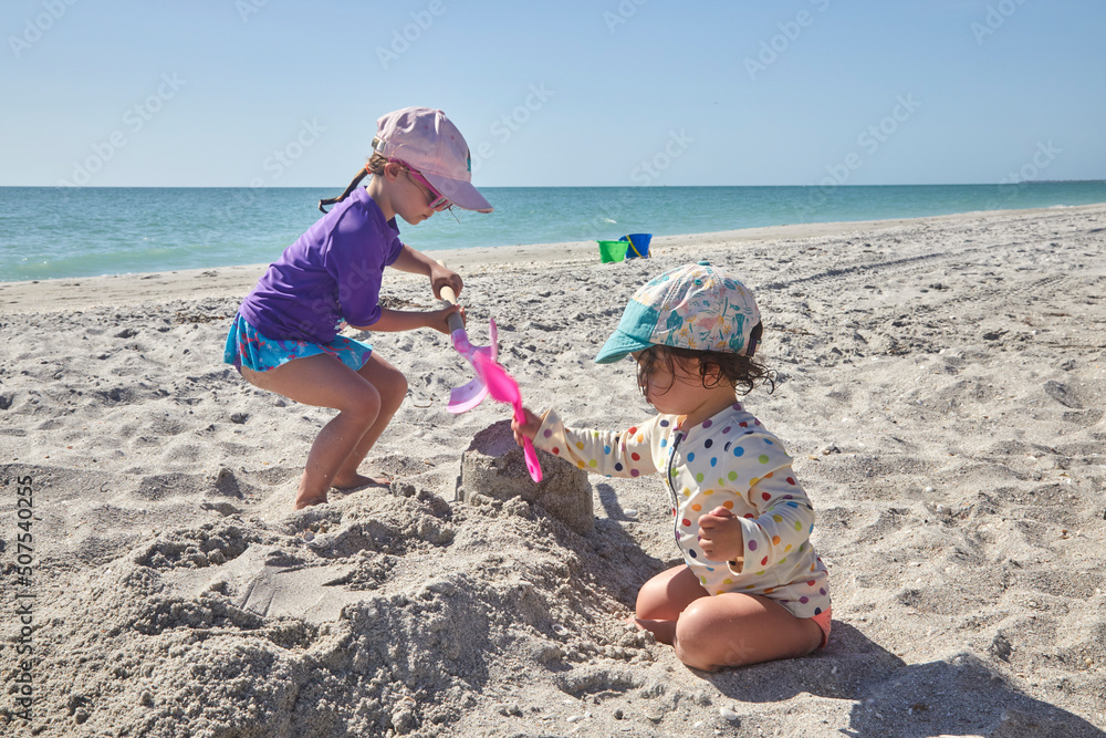 Two little girls playing in the sand on a family vacation at the beach Two little girls playing in the sand on a family vacation at the beach