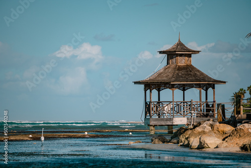 Canvas Print Wooden arbour near tropical sea, low tide, evening