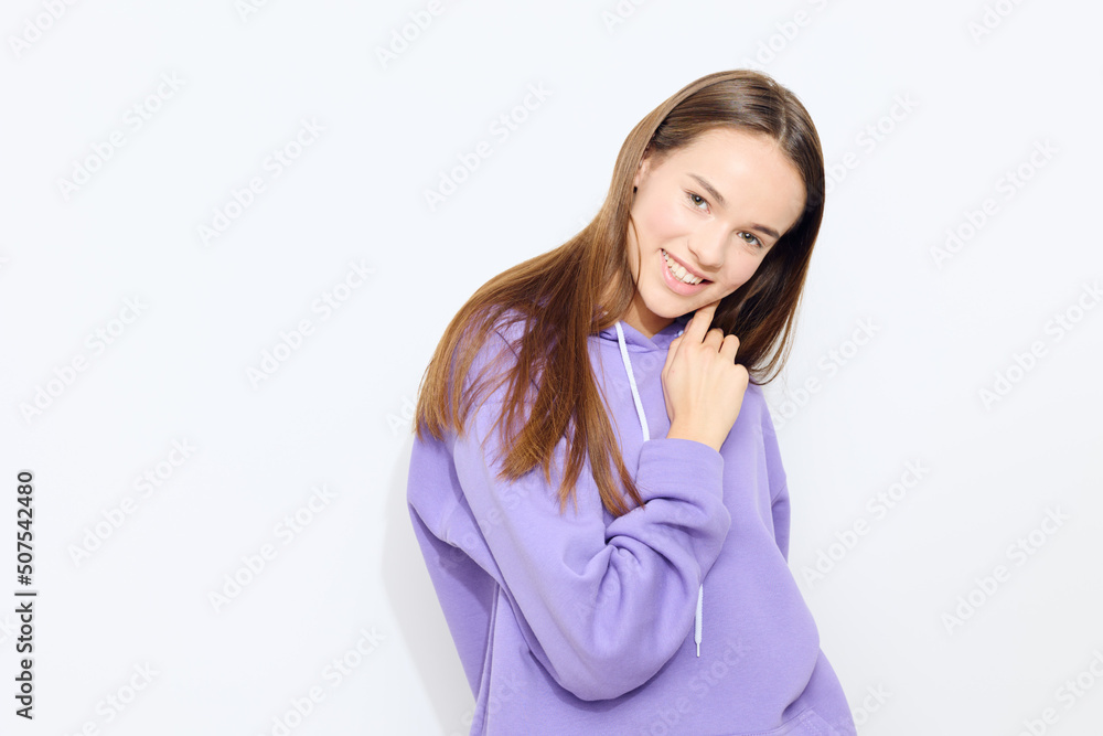 an emotional woman stands on a white background in a purple tracksuit slightly adjusting her hair with one hand hiding the other behind her back an emotional woman stands on a white background in a purple tracksuit slightly adjusting her hair with one hand hiding the other behind her back