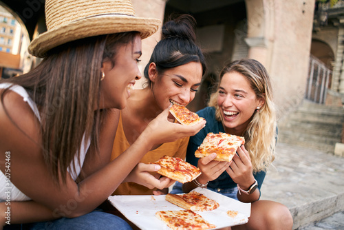 Canvas Print Funny group of three girls eating pizza in the city