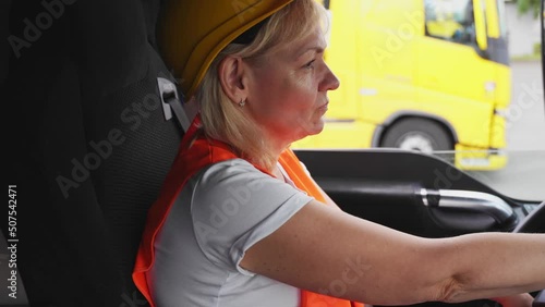 Mature woman truck driver steering wheel inside lorry cabin. Happy middle age female trucker portrait 