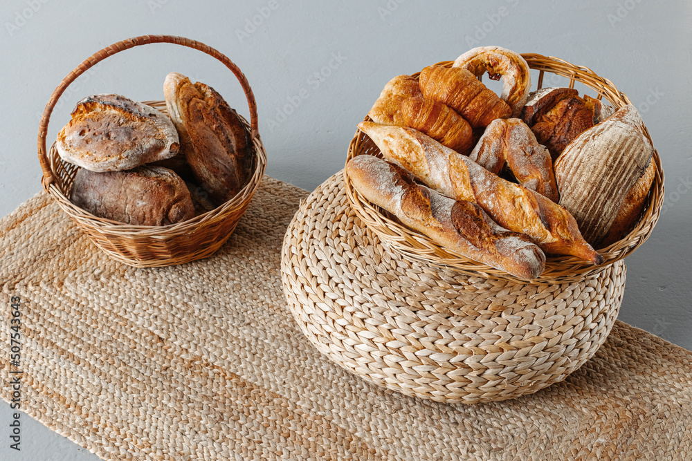 Basket with bread on a decorative burlap carpet. Culinary baking background.