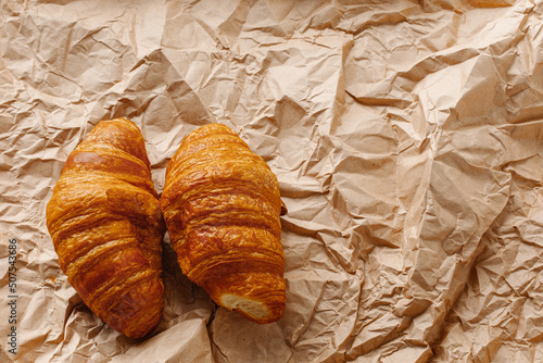 Culinary background. Two croissants close up on a brown paper background.