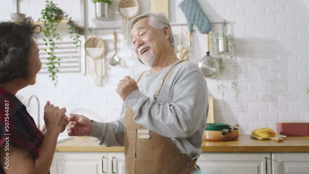 Asian mature senior couple is dancing and smiling in kitchen at home. Asian mature senior couple is dancing and smiling in kitchen at home.