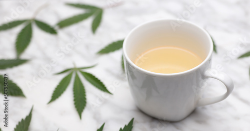 marijuana-infused white mug, on marble table with leaves 