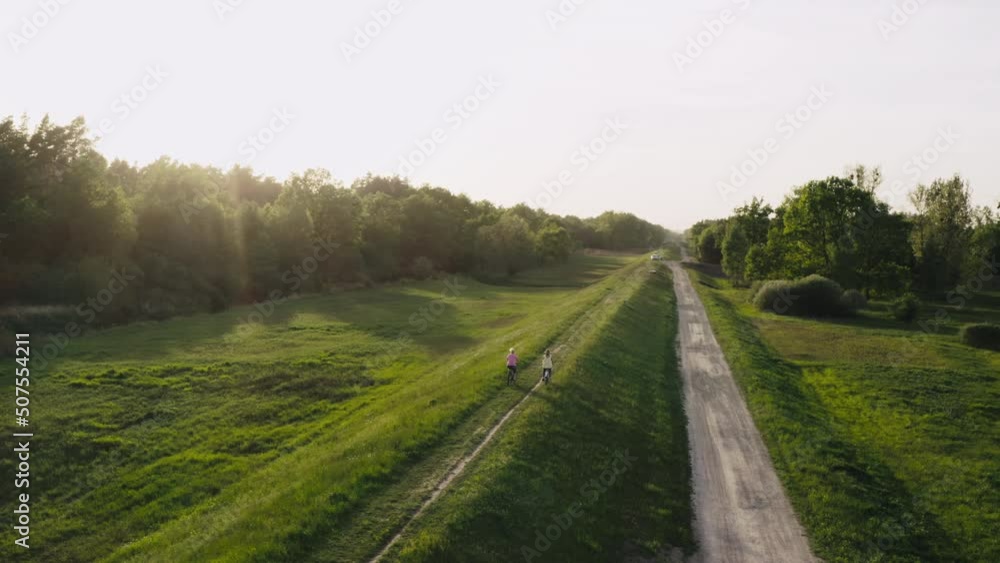 Two girl girlfriends riding bicycles in the park at sunset. Beautiful nature and active recreation of women friends.Aerial view. Two girl girlfriends riding bicycles in the park at sunset. Beautiful nature and active recreation of women friends.Aerial view.