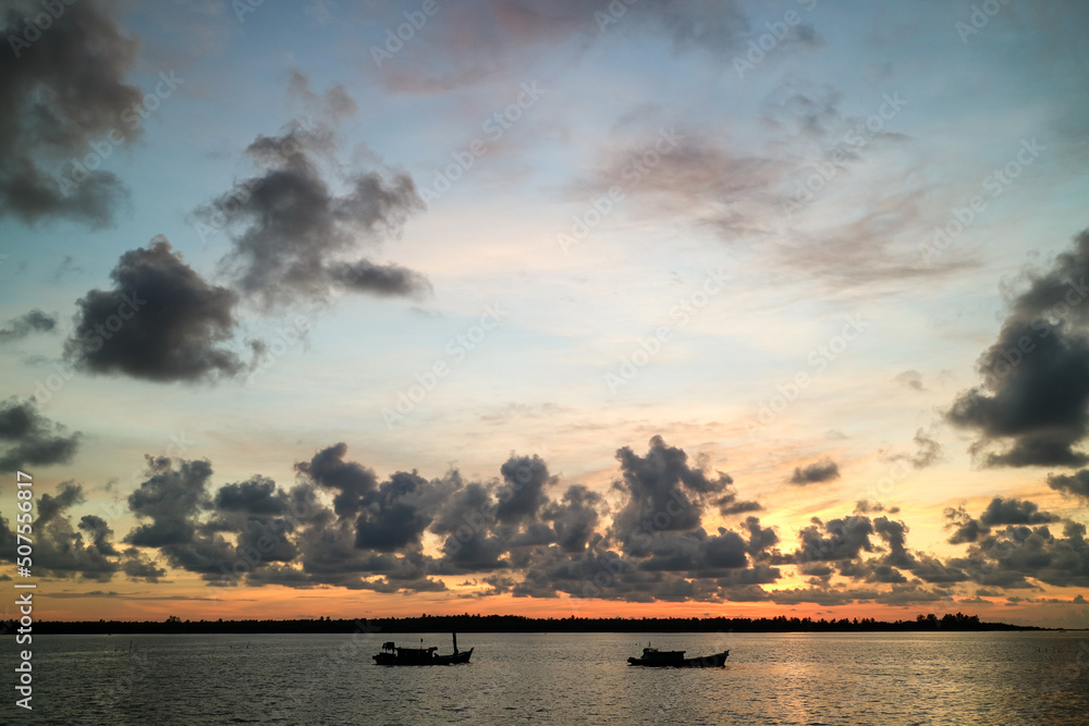 Naklejka premium Sunset over the river. Silhouette of small boats at sunset.