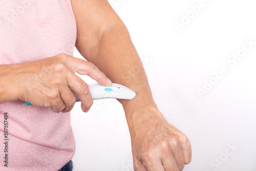 Fotografia A woman treats a mosquito bite on her arm with an electric bite healer - isolated on white background
