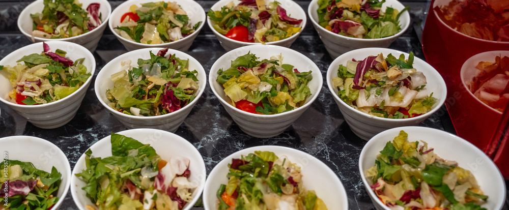 Green vegan salad from green leaves mix and vegetables, side view. set with different salads on table Green vegan salad from green leaves mix and vegetables, side view. set with different salads on table