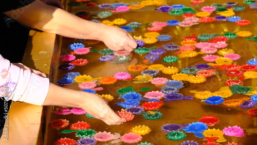 Hands of people floating colorful candle floating on water for pray at the temple.