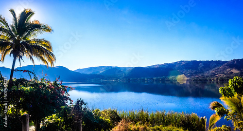 panoramic of blue lagoon with mountains in the background and palm tree in first plane in a sunny day in santa maria del oro nayarit photo