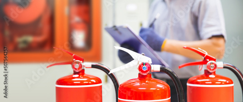 Fire extinguisher has hand engineer inspection checking pressure gauges to prepare fire equipment for protection and prevent emergency and safety rescue and alarm system training concept. © Eakrin