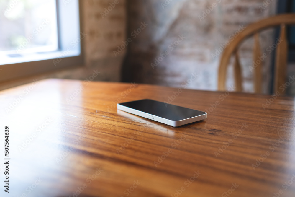 A single mobile phone on wooden table A single mobile phone on wooden table