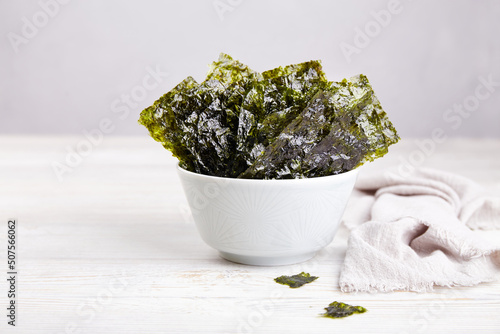 Crispy nori seaweed on bowl on grey background. Traditional Japanese dry seaweed sheets. Healthy snack.  photo