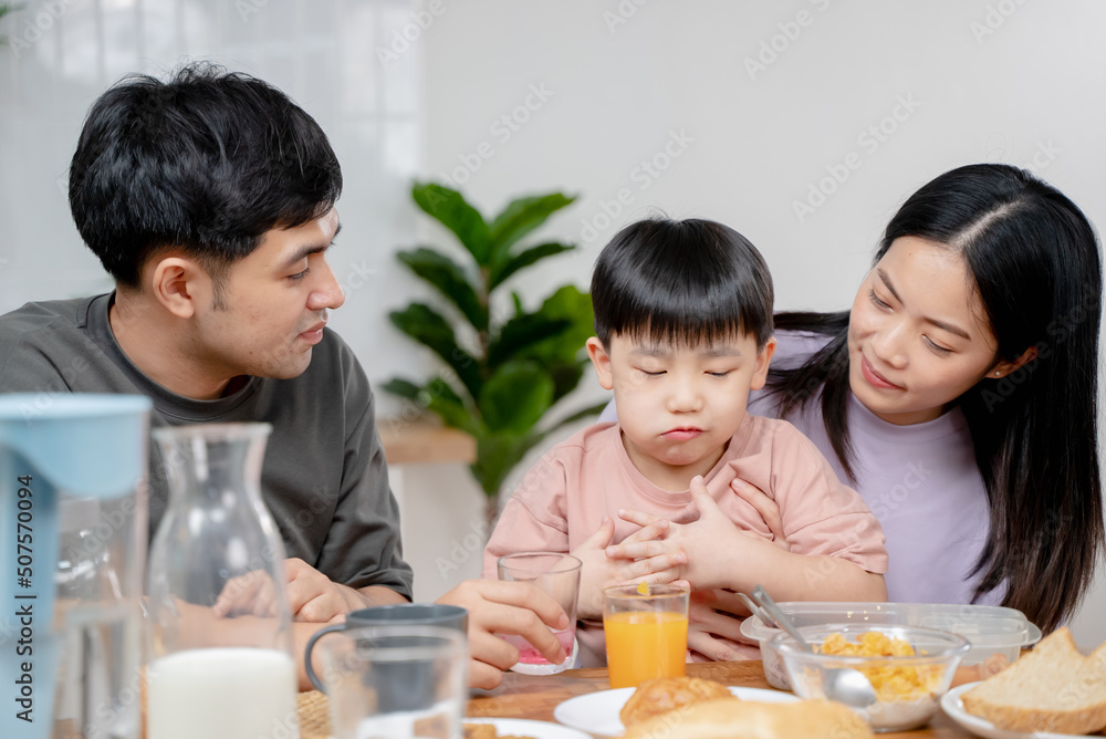 happy family together. Asian parent eating breakfast with little son in the kitchen. happy family together. Asian parent eating breakfast with little son in the kitchen.