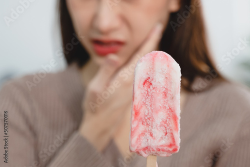Asian Woman touching her chin feeling sensitive teeth when eating an ice cream. Have a gum and oral problem. photo