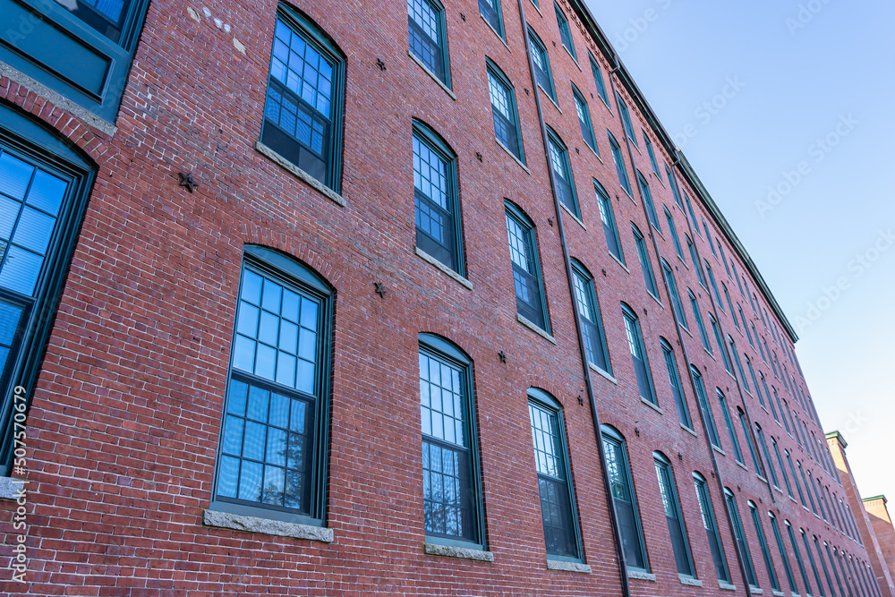 The fasade of a historic cotton factory building in an old industrial park on the Nashua River in May. Nashua, New Hampshire, USA The fasade of a historic cotton factory building in an old industrial park on the Nashua River in May. Nashua, New Hampshire, USA