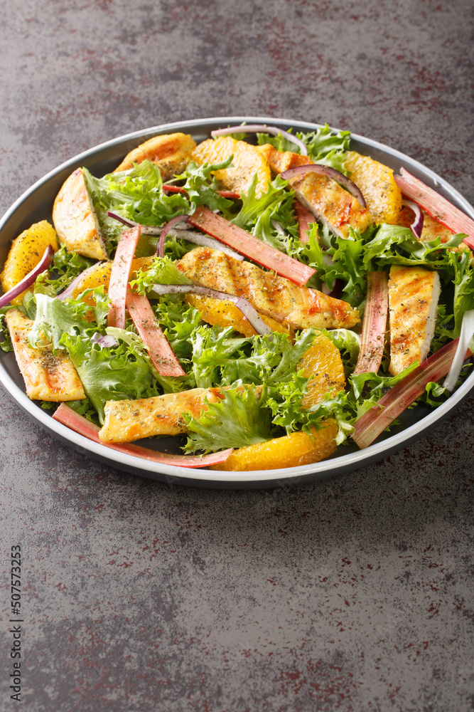 Rhubarb and chicken salad with oranges, onions and lettuce closeup on the wooden board on the table. Vertical Rhubarb and chicken salad with oranges, onions and lettuce closeup on the wooden board on the table. Vertical