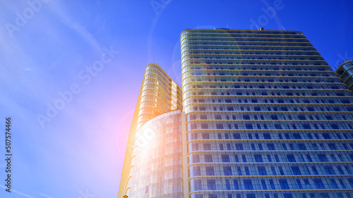 Reflection of the sun in the glass facade of a tall modern building. Business corporate construction industry and real estate financial. Urban scenery with sun light. 