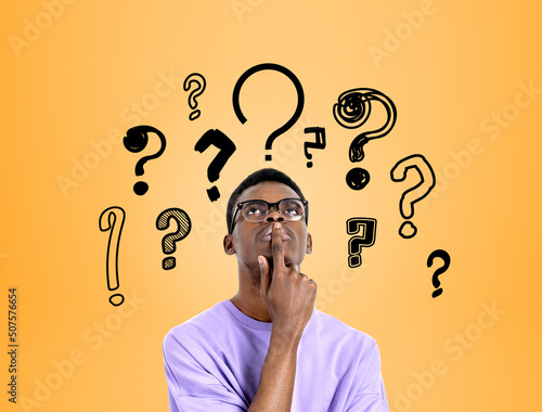 Fotografia Young black man with pensive look, set of question marks on brig
