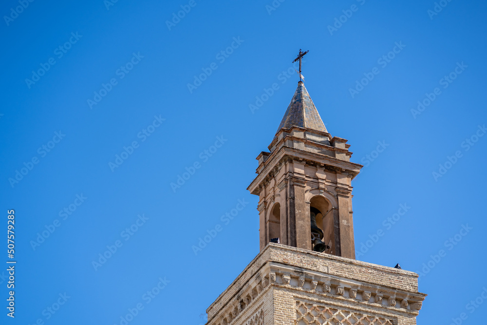 The stone tower of the church in the old town of Spain is a cross with a blue sky
