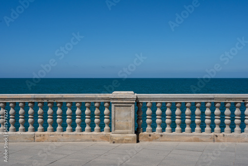 a promonade in spain along a oceanfront where there are tiles and a concrete fence in the blue of the ocean with clear blue skies photo
