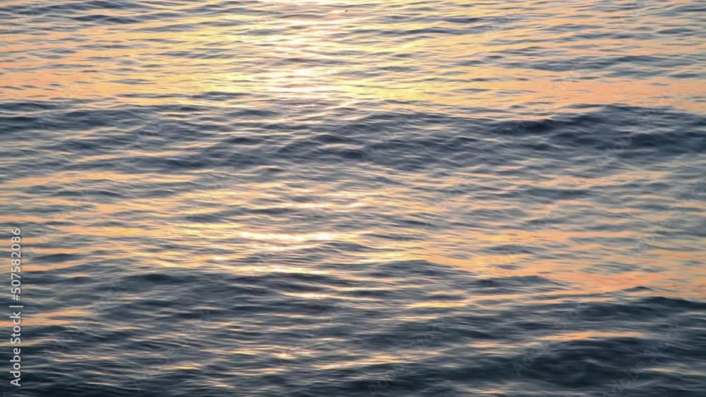 Orange sea water at sunset. Sun reflects and sparkles on waves with light trail. Real time 4K resolution video. Abstract summer natural background. Copy space for your text. Orange sea water at sunset. Sun reflects and sparkles on waves with light trail. Real time 4K resolution video. Abstract summer natural background. Copy space for your text.