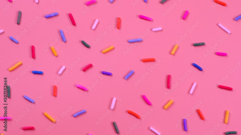 A rotation background of sprinkles for sweets on a pink background.The concept of celebrating a birthday, party or other holidays.fashionable,sweet background A rotation background of sprinkles for sweets on a pink background.The concept of celebrating a birthday, party or other holidays.fashionable,sweet background